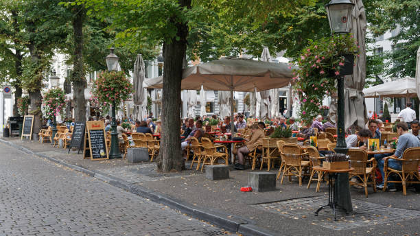 People on a sidewalk cafe at the square in front of the "Basiliek van Onze-Lieve-Vrouw" downtown Maastricht stock photo