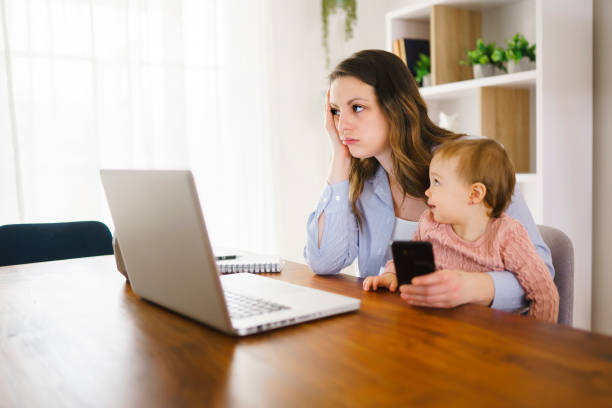 istock sad and frustrated mother in kitchen home office with computer and her daugher 1313847066