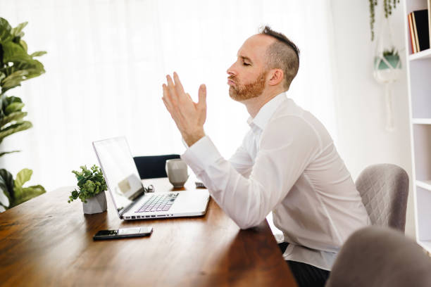 istock frustrated and sad man working on laptop at home 1313847084