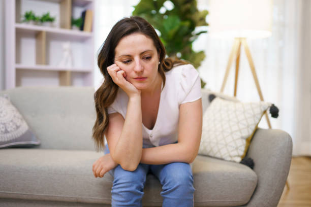 istock Stressed mature woman sitting on sofa at home look sad 1313847352