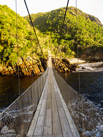 Straight on view of the Suspension bridge crossing the Storms River Mouth, Tsitsikama, Garden Route National Park, South Africa in the late afternoon