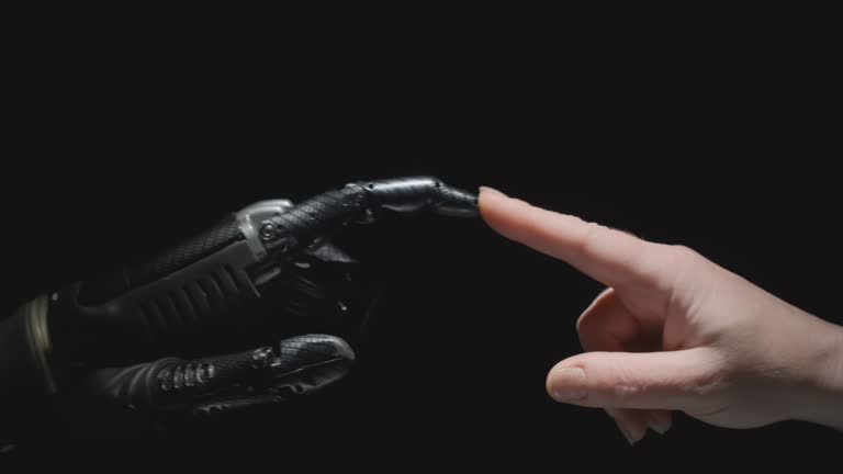 Humanoid robot arm and human hand reach out to each other and touch with fingers on black background.