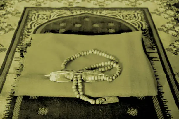 Old mode of Sajadah carpet with a turban and a tasbeeh prayer beads