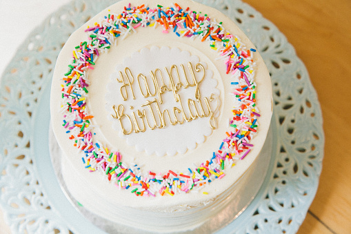 Vanilla icing cake with sprinkles with a Happy Birthday message on top of it