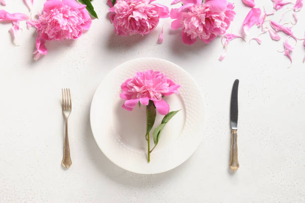 istock Festive table setting with pink peony flowers on a white table. View from above. 1313855886
