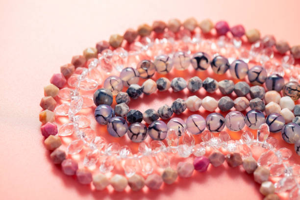 istock Crystal drop beads, faceted and smooth round natural stone beads on threads on a pink background 1313856015