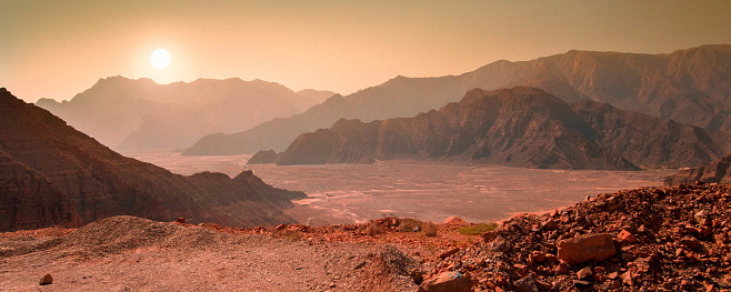 Landscape on the panet Mars with mountain range and sun. In reality the photo was made in the desert of Musandam, Oman, near the city of Khasab.