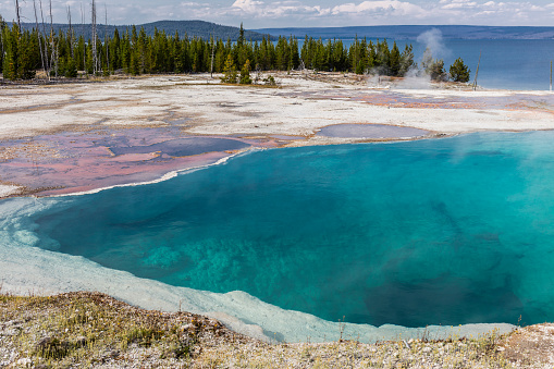 Yellowstone National Park, Teton County, Wyoming, United States. West Thumb Geyser Basin. Abyss Pool with Yellowstone Lake in the background.