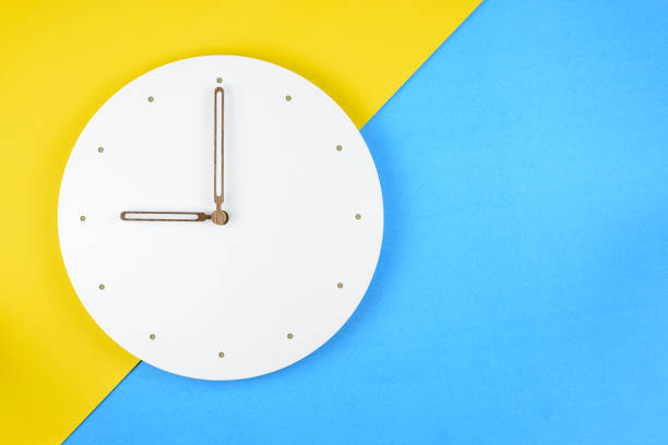 istock Top or above view / flat lay of a white clock on yellow-blue background, depicts resting, refresh period during hard work in business day 1313862101