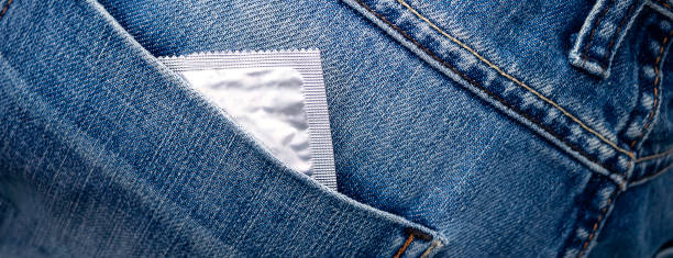 banner with Close-up of a condom peeking out of the back pocket of blue jeans stock photo