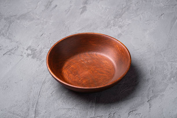 istock Empty round handcrafted brown wooden plate on stone concrete background, angle view 1313865138