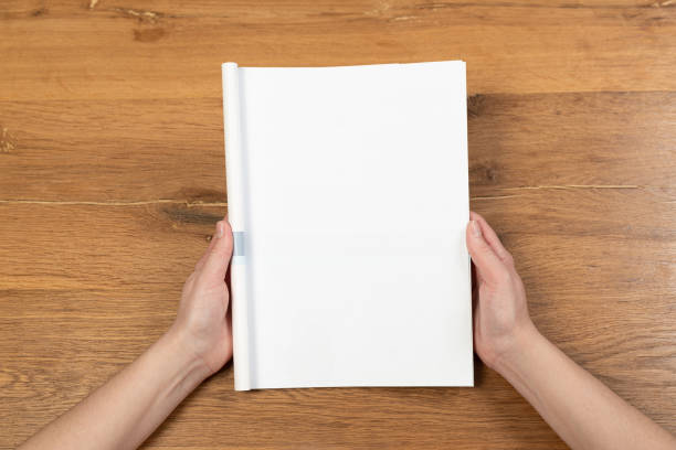 istock Woman's hands open empty catalog, magazines, book mockup on wooden table 1313867244