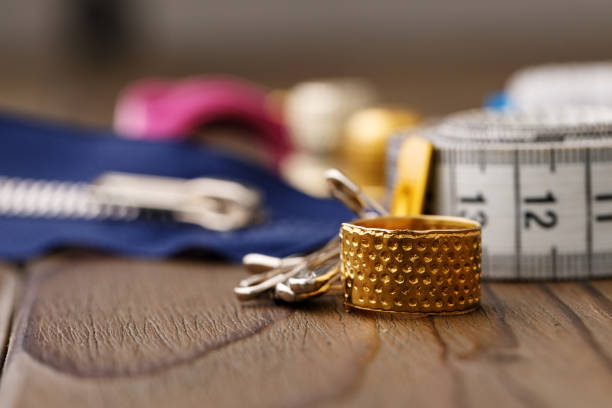 Thimble and measuring tape on wooden table close up