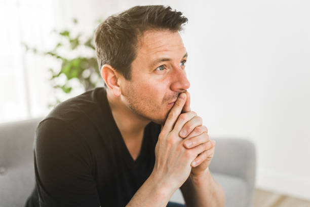 istock Depressed and thinking man thinking at home on couch 1313877171