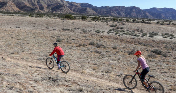 istock Female mountain bikers follow desert pathway 1313877614