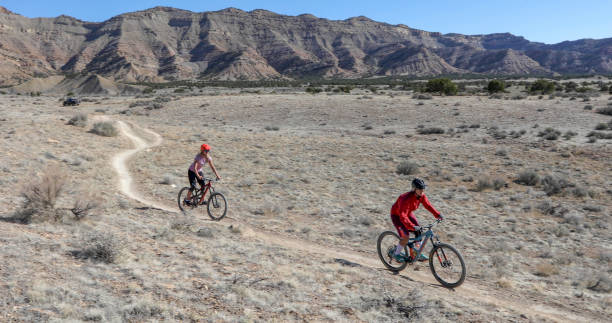 istock Female mountain bikers follow desert pathway 1313877649