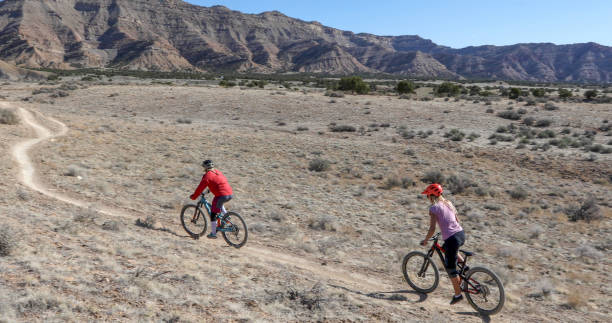 istock Female mountain bikers follow desert pathway 1313877670
