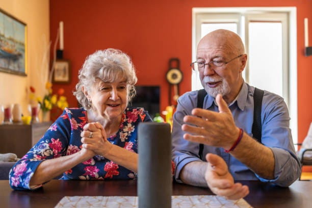 casal sênior animado usando um assistente virtual em casa - senior couple audio - fotografias e filmes do acervo