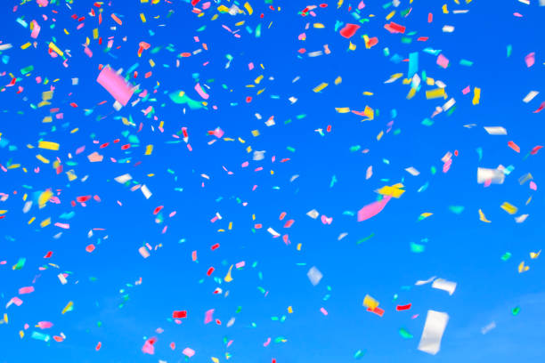 istock multicolored confetti on clear blue sky background. Concept of h 1313879520