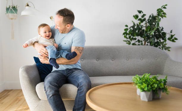 istock father playing with cute baby daughter on the sofa 1313880645