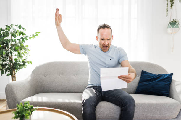 istock Shocked man holding some documents on sofa livingroom 1313880716