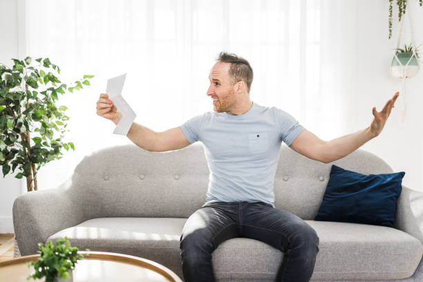 istock Shocked man holding some documents on sofa livingroom 1313880779