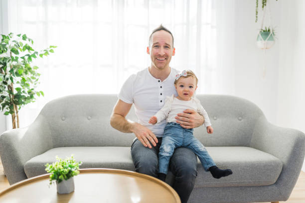 istock father playing with cute baby daughter on the sofa 1313880900