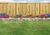 Empty backyard with green grass, wood fence and flowerbed