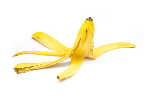 Vista al suelo del plátano pelado sobre fondo blanco. Pisar una cáscara de plátano photo