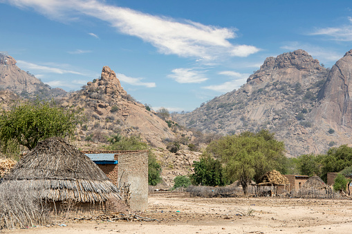 Typical Chadian village in front of the Guera Massif. \n\nThe province of Guéra, located in central Chad, about 500 km from the capital N'Djamena, is settled by cattle breeders and agricultural farmers, who live in a synergic relationship in which the mountains are sacred and are home to the Margay, the ancestor spirits of the Animist culture.