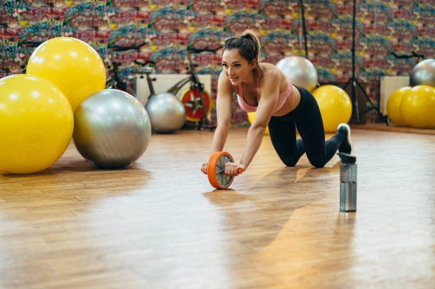 istock Woman training in the gym while using a wheel for abs 1313888080