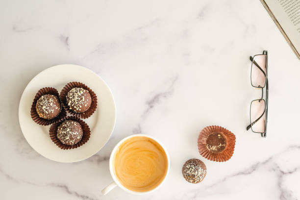 l’heure du café, prendre un concept de pause. tasse de café, bonbons au chocolat, livre, verres se ferment vers le haut sur le bureau de marbre, plat laïe, espace de copie. - snack coffee instant coffee cappuccino photos et images de collection