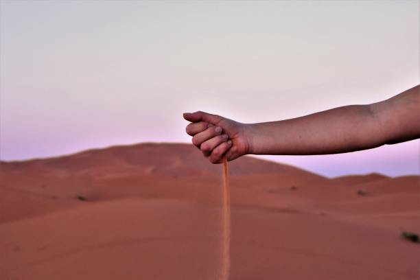 Hand of Sand; Hand of Time Woman dropping sand into Sahara Desert with dune in background. indegious culture stock pictures, royalty-free photos & images