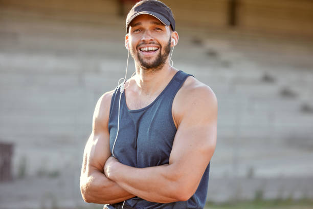 foto de un joven deportivo con los auriculares y de pie con los brazos cruzados fuera - arms crossed audio fotografías e imágenes de stock