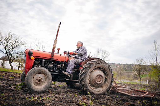 senior farmer riding tractor on his farm.