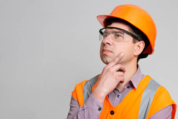 istock Young engineer architect in hard hat and reflective vest thinking with hand under chin, building industry concept 1313893668