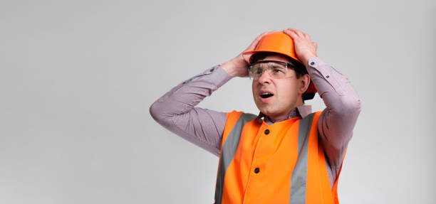 istock young engineer architect clutching his head in helmet on grey studio background, foreman shocked 1313893692