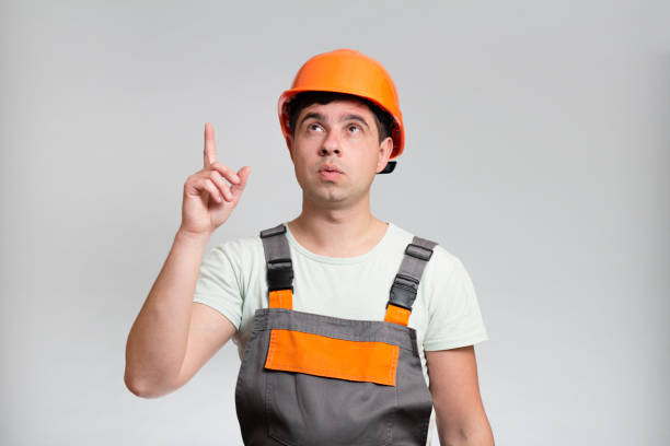 istock Young construction worker in hard hat and reflective vest raised finger up as sign he has new idea on studio background 1313893738