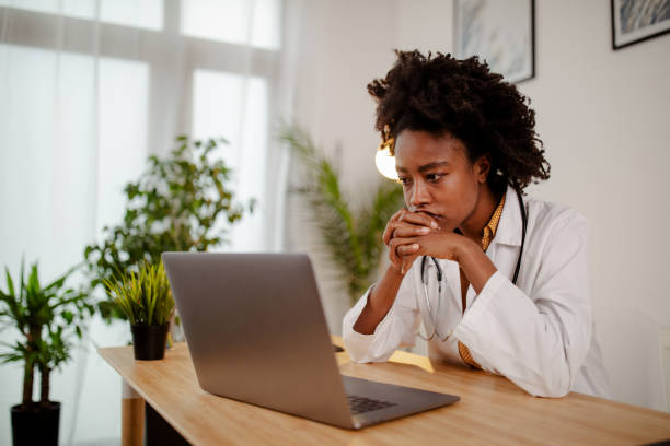 Worried black female doctor working on computer at her desk. stock photo