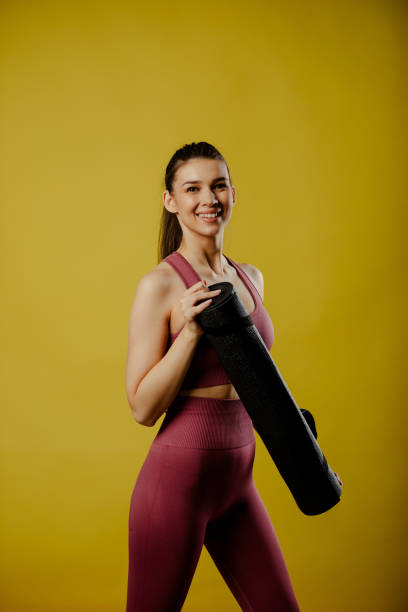 istock Smiling fit girl is posing on yellow background with mat. 1313896178