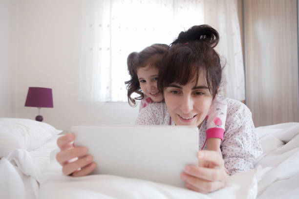 istock Happy woman with daughter using digital tablet on bed 1313897950