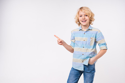 Caucasian preteen boy in casual clothes pointing at copy space isolated on white
