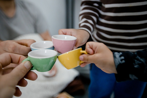 Twins and parents toast with toy teacups