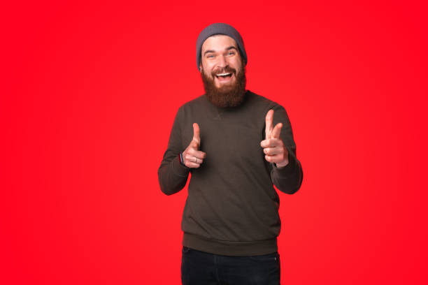 istock An excited bearded young man is smiling at the camera while is pointing with both hands at it 1313902178