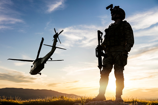 Silhouette of standing soldier in battlefield at sunset