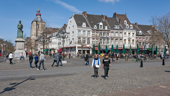 Maastricht, Limburg, Netherlands, april 20th 2013, large group of people enjoying the beautiful weather on their free Saturday at sidewalk cafe's on the Market square downtown Maastricht on a sunny day at springtime, others are walking by or just sitting on the square itself - the square has a rich history and many monumental buildings surrounding it, 62 of which are a national heritage site (