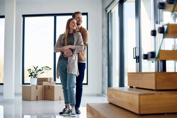 istock Happy couple standing embraced and day dreaming while moving into their new home. 1313909769