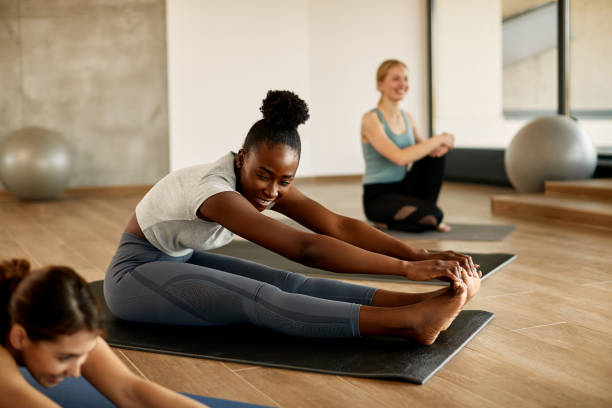 istock Happy black athletic woman doing stretching exercise while practicing Pilates with group of women in health club. 1313909844