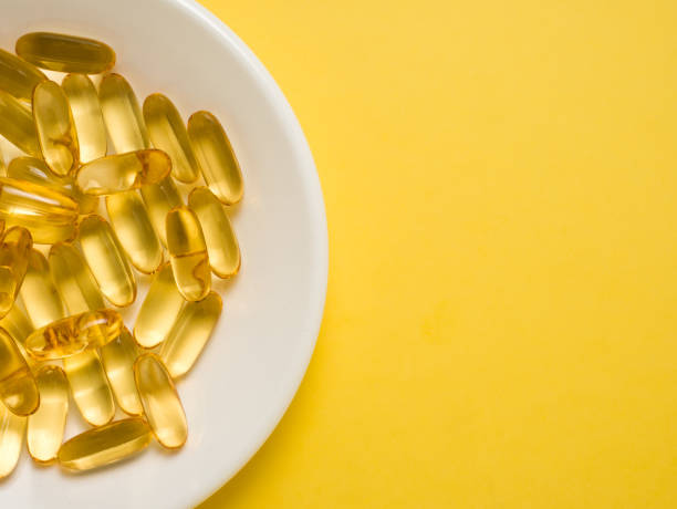 istock Vitamin D tablets capsules in a white plate on a yellow background 1313910088