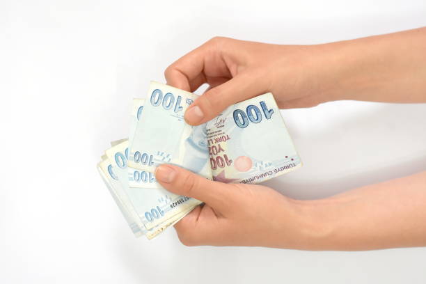 istock Hands holding Turkish lira bills isolated on white background. 1313910158